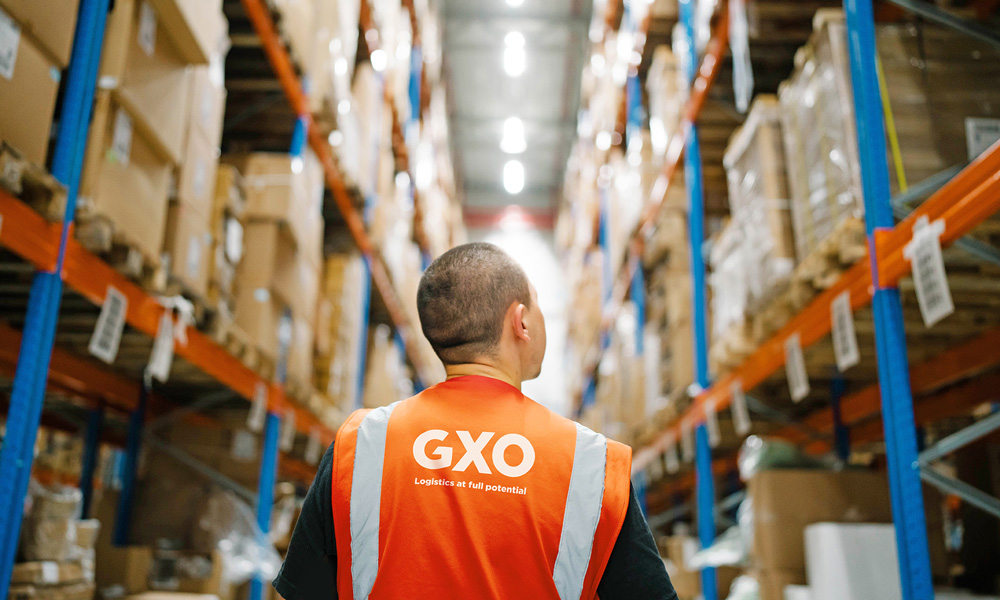GXO employee from behind, looking up at the contents of a warehouse rack